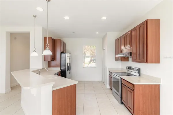 a large kitchen with stainless steel appliances granite countertop a stove a sink and a refrigerator