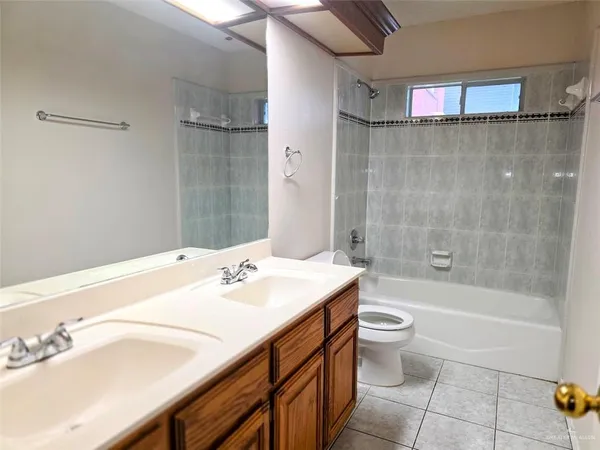 a bathroom with a granite countertop bathtub shower sink vanity and toilet