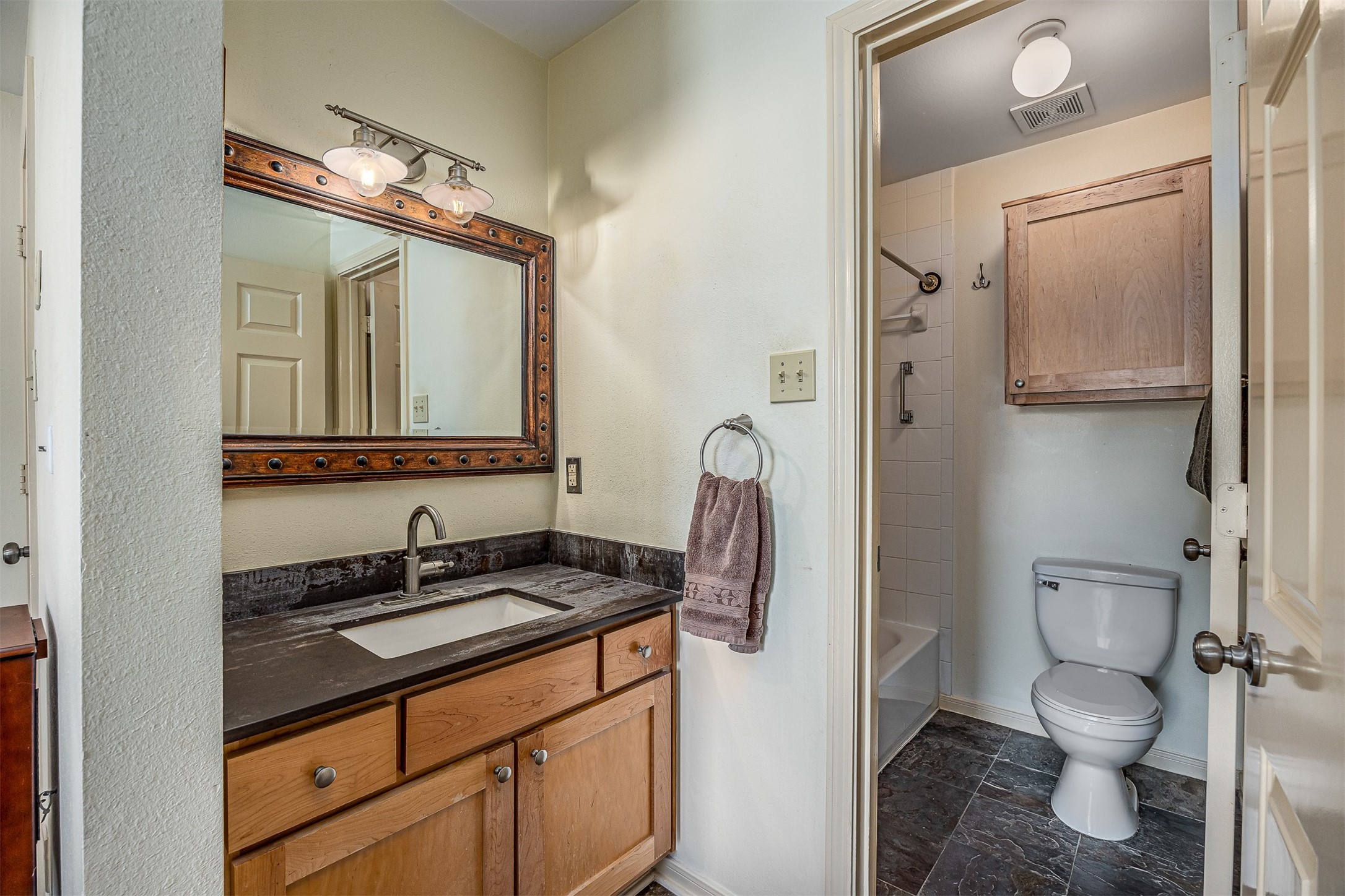 1505 Ward Road, Unit 128 Baytown, TX 77520 - Photo 15 of 21 This en-suite bathroom features a modern vanity with a dark countertop and wooden cabinets, complemented by a large framed mirror.