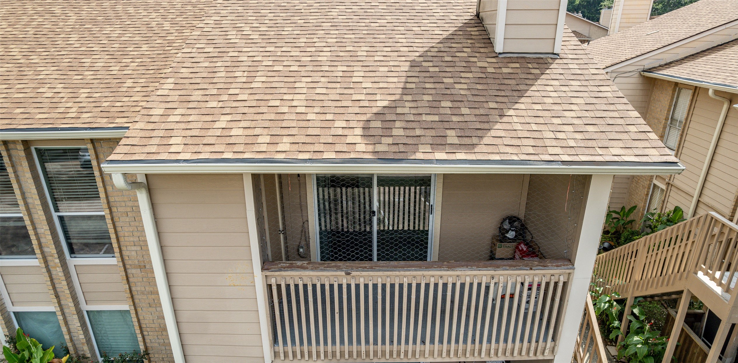 1505 Ward Road, Unit 128 Baytown, TX 77520 - Photo 3 of 21 This photo shows a condo with a cozy balcony, featuring a sliding glass door and wood railing. The building has a shingled roof and beige siding, providing a warm, inviting exterior.