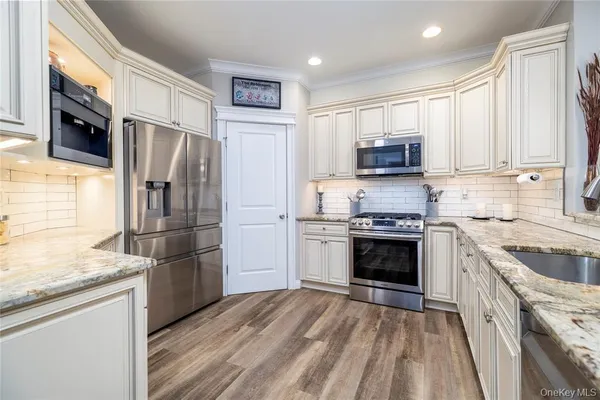 a kitchen with granite countertop a refrigerator stove and microwave