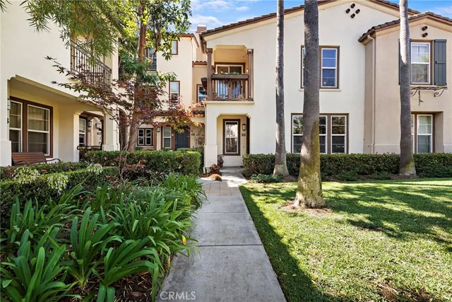a view of a brick house with many windows plants and large trees
