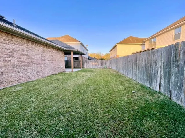 a backyard of a house with lots of green space and wooden fence