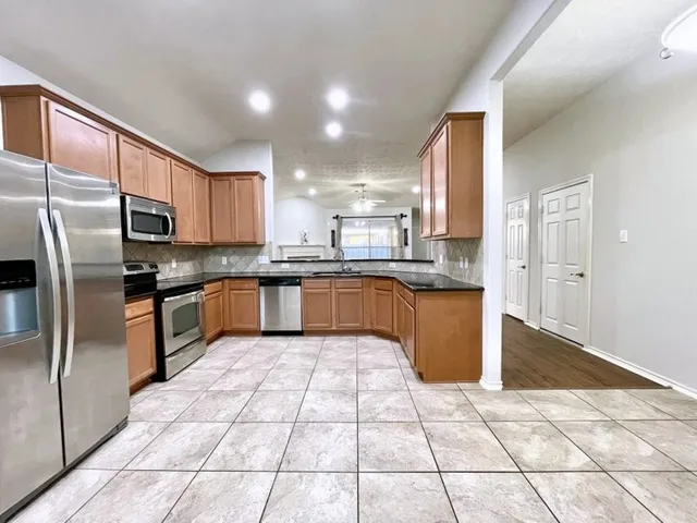 a large kitchen with stainless steel appliances granite countertop a stove a sink dishwasher a refrigerator and cabinets