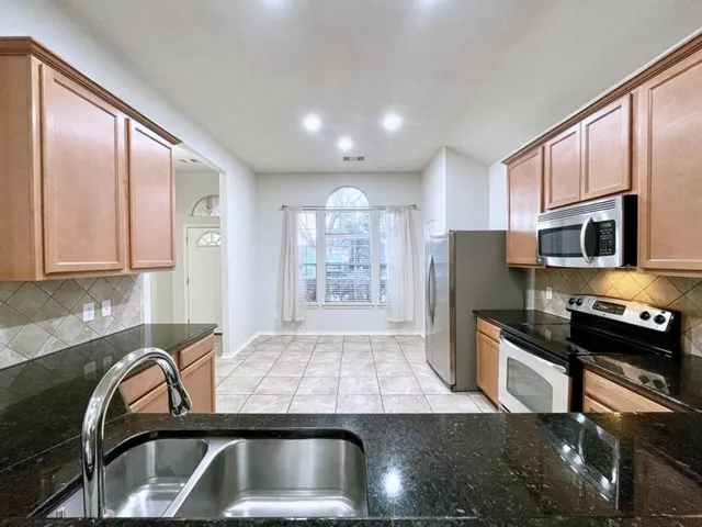 a kitchen with a sink a counter top space cabinets stainless steel appliances and a window