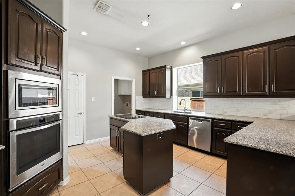 8220 Holliday Road Lantana, TX 76226 - Photo 15 of 40 Kitchen featuring dark wood-finish cabinetry, light-toned granite-style countertops, and a subway tile backsplash