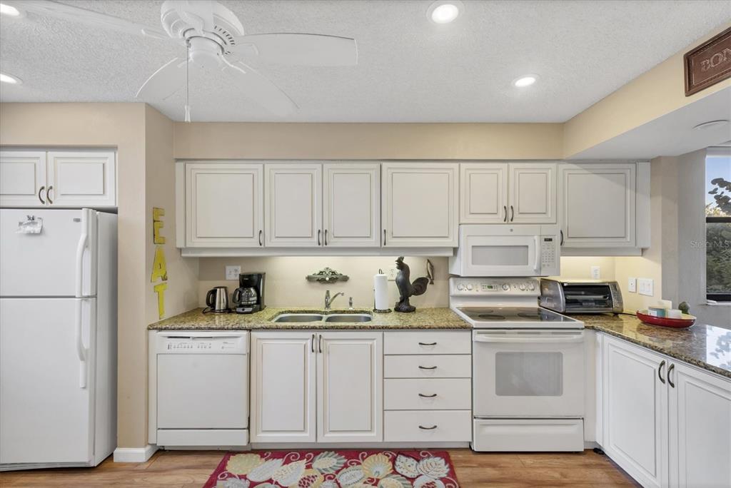 825 Bayport Way, Unit 825 Longboat Key, FL 34228 - Photo 31 of 62 a kitchen with granite countertop white cabinets and white appliances