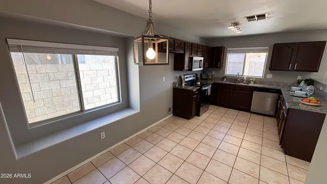 a kitchen with a refrigerator a stove top oven a sink a dining table and chairs