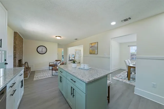 a hall with kitchen island a sink dishwasher a dining table and chairs with wooden floor