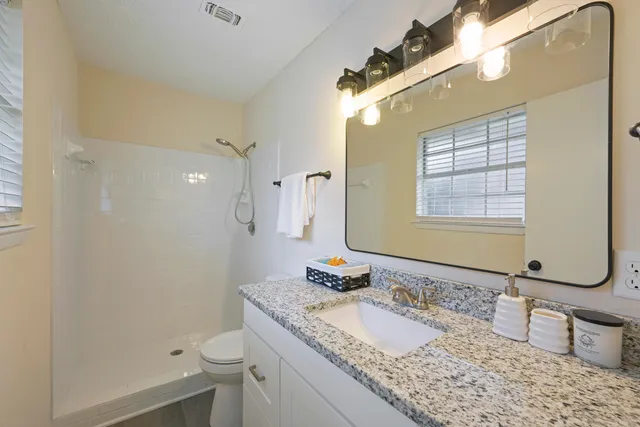 a bathroom with a granite countertop sink toilet and shower