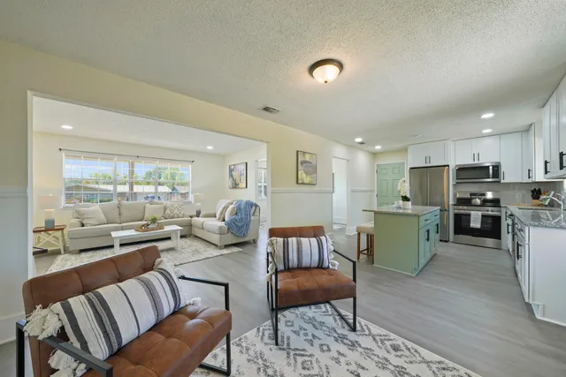 a living room with furniture kitchen area and a wooden floor