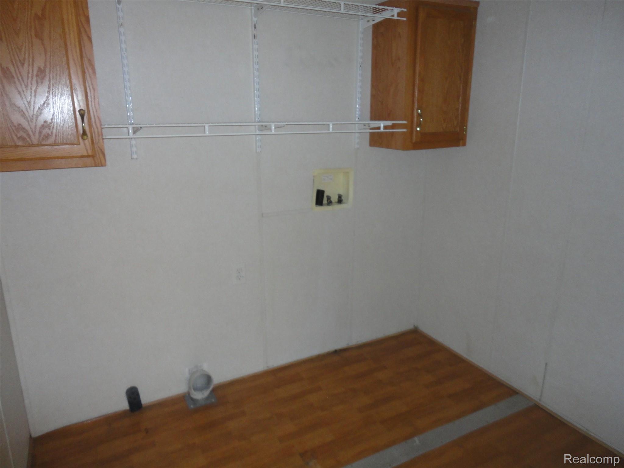 3954 Ryans Ridge Monroe, MI 48161 - Photo 13 of 28 Laundry area featuring wood-finish flooring, two wall-mounted storage cabinets with brass-tone hardware, and wire shelving