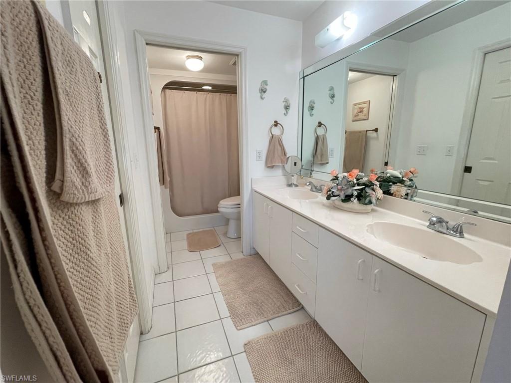 153 Gabriel Circle, Unit 3003 Naples, FL 34104 - Photo 11 of 38 a bathroom with a double vanity sink a toilet a mirror and bathtub