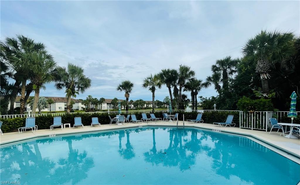 153 Gabriel Circle, Unit 3003 Naples, FL 34104 - Photo 34 of 38 a view of swimming pool with outdoor seating and trees in the background