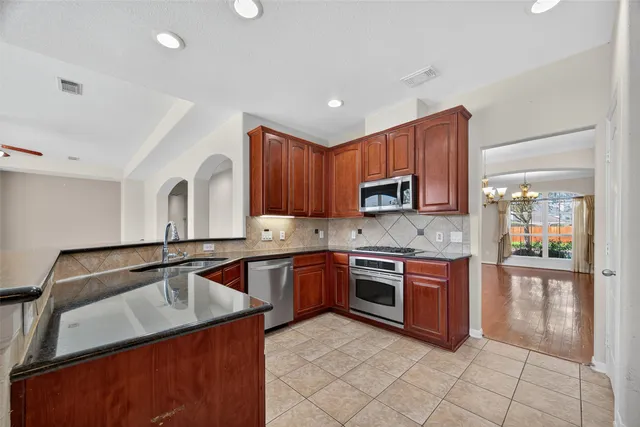 a kitchen with stainless steel appliances granite countertop a sink stove and cabinets
