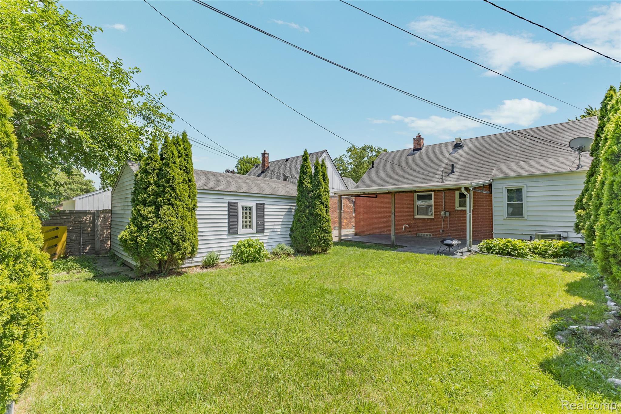 26508 Five Mile Road Redford, MI 48239 - Photo 36 of 41 Expansive backyard featuring a manicured lawn, dedicated patio space, and a detached auxiliary building