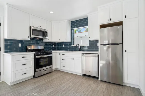a kitchen with stainless steel appliances white cabinets and a refrigerator
