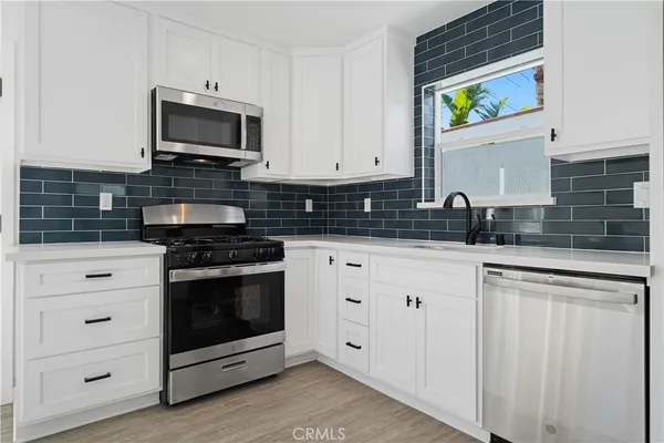 a kitchen with white cabinets and appliances
