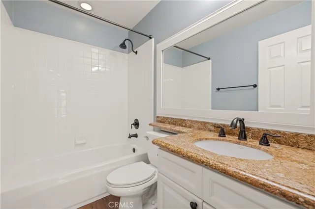 a bathroom with a granite countertop sink a toilet and shower