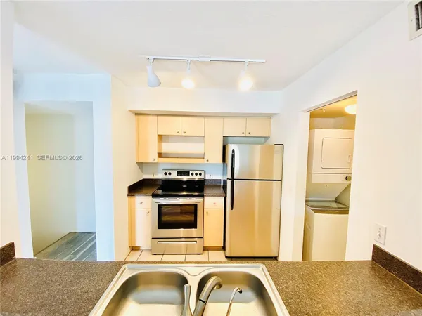 a kitchen with a refrigerator a stove and a sink with wooden floor