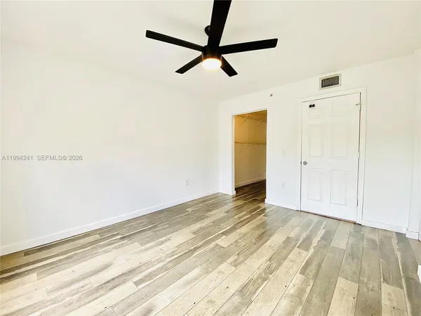 a view of a room with wooden floor and a ceiling fan