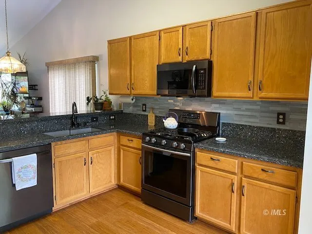 a kitchen with stainless steel appliances granite countertop a stove a sink and a microwave