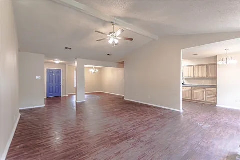 an empty room with wooden floor fireplace and windows