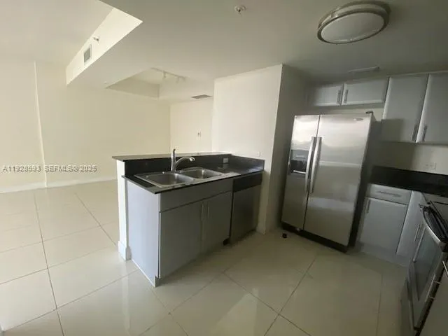 a kitchen with stainless steel appliances granite countertop a sink and a refrigerator