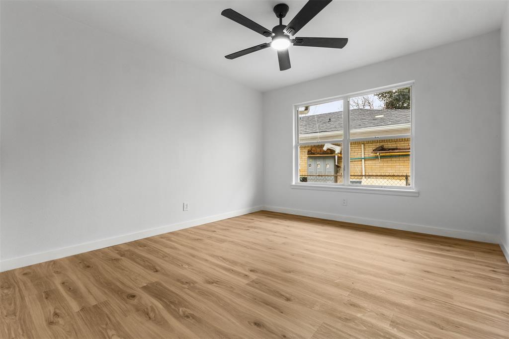 1917 South Vernon Avenue Dallas, TX 75224 - Photo 20 of 28 Spacious room featuring wood-finish flooring, a contemporary ceiling fan with integrated lighting, white walls, and a large window with white trim