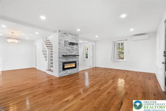 a view of an empty room with a fireplace and wooden floor
