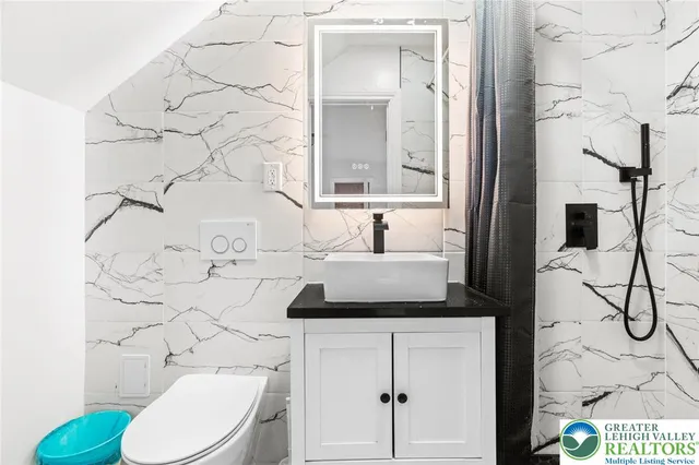 a bathroom with a granite countertop sink and a toilet