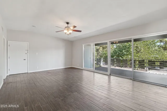 a view of an empty room with wooden floor and a window