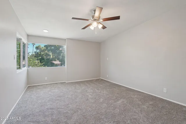 an empty room with windows and ceiling fan