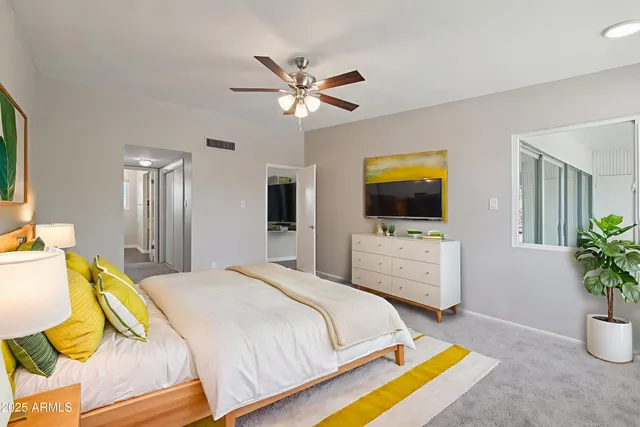 a bedroom with a bed a flat screen tv and a chandelier