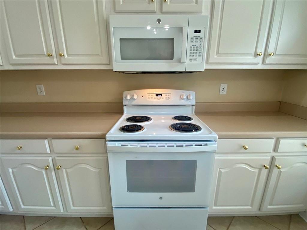 1698 Pin Oak Drive, Unit 129 Dalton, GA 30721 - Photo 13 of 37 a kitchen with white cabinets and white appliances