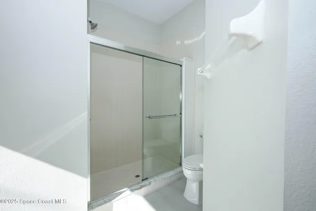 a bathroom with a granite countertop toilet and a shower