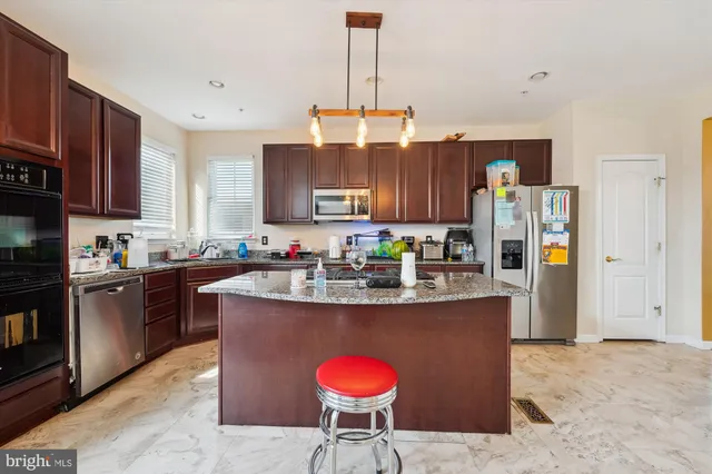 a kitchen with stainless steel appliances granite countertop a kitchen island a stove a refrigerator and a refrigerator