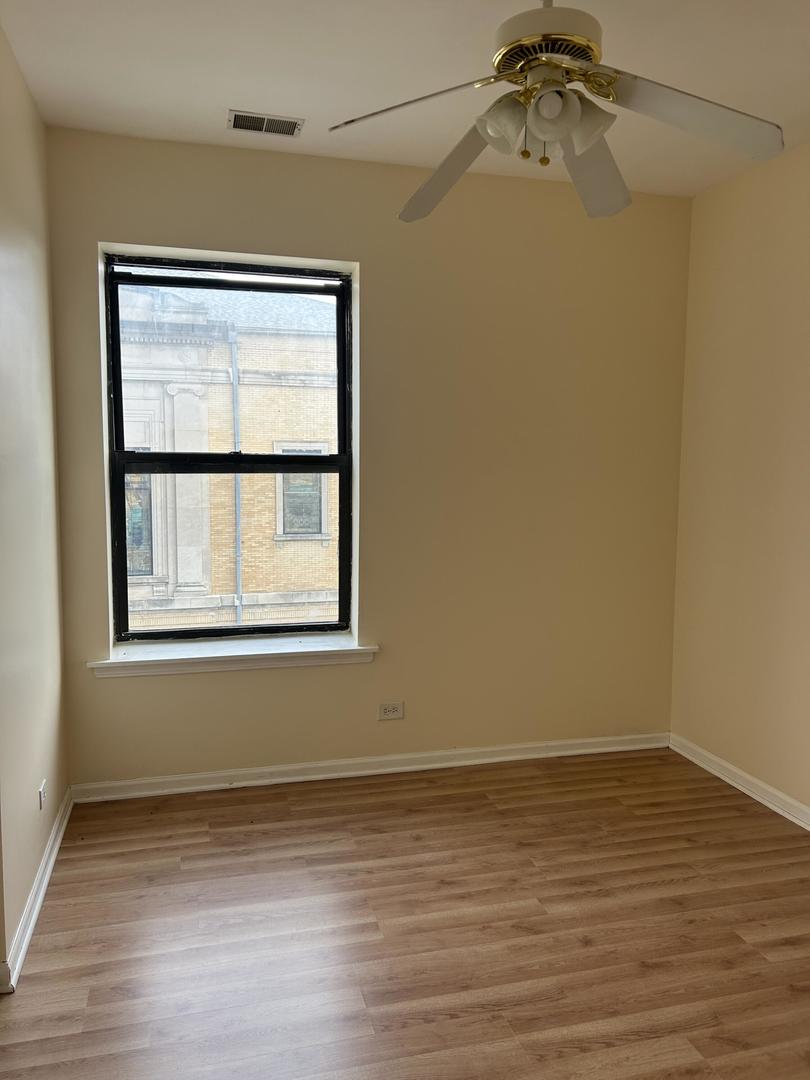 800 South Independence Boulevard, Unit 3 Chicago, IL 60624 - Photo 8 of 12 a view of an empty room with wooden floor and a window