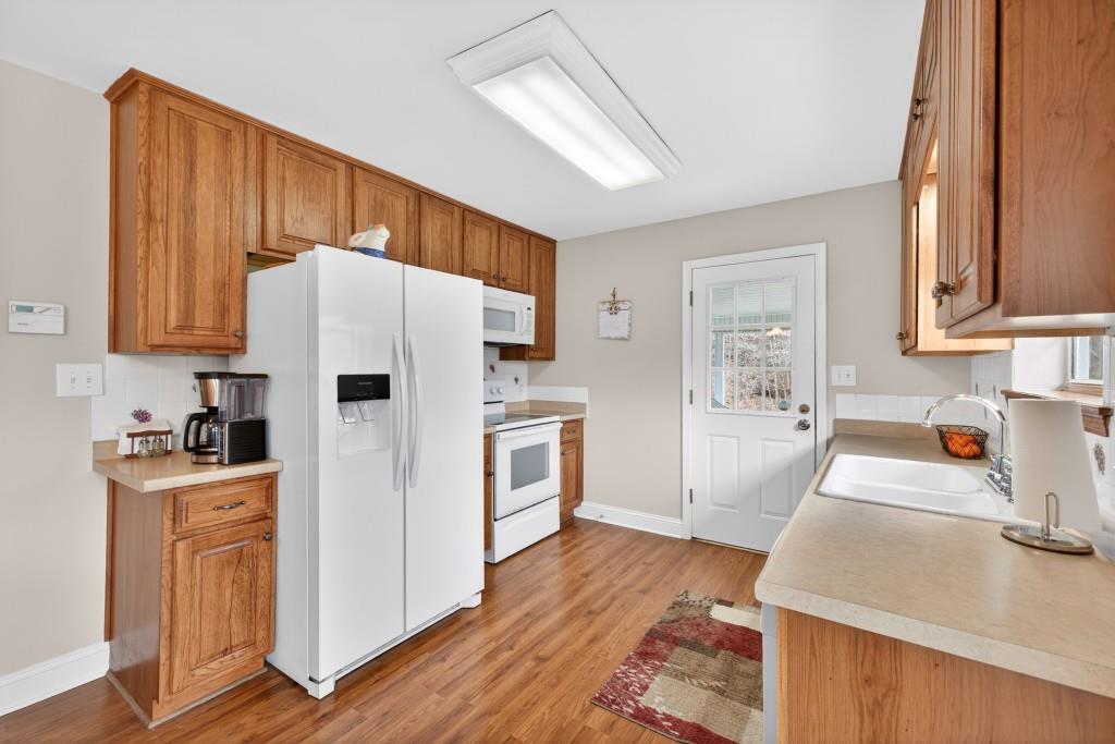 335 Ranger Way Braselton, GA 30517 - Photo 8 of 63 a kitchen with granite countertop wooden floors and white stainless steel appliances