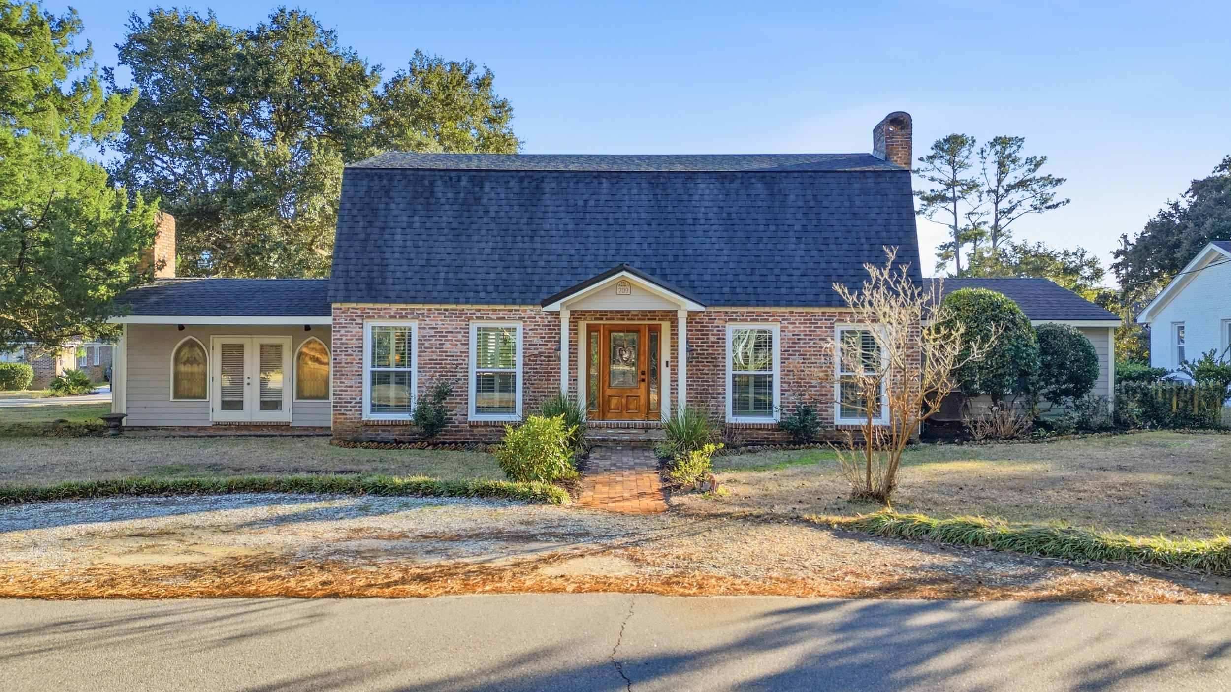 Colonial inspired home with a shingled roof, a chimney, brick siding, a gambrel roof, and french doors