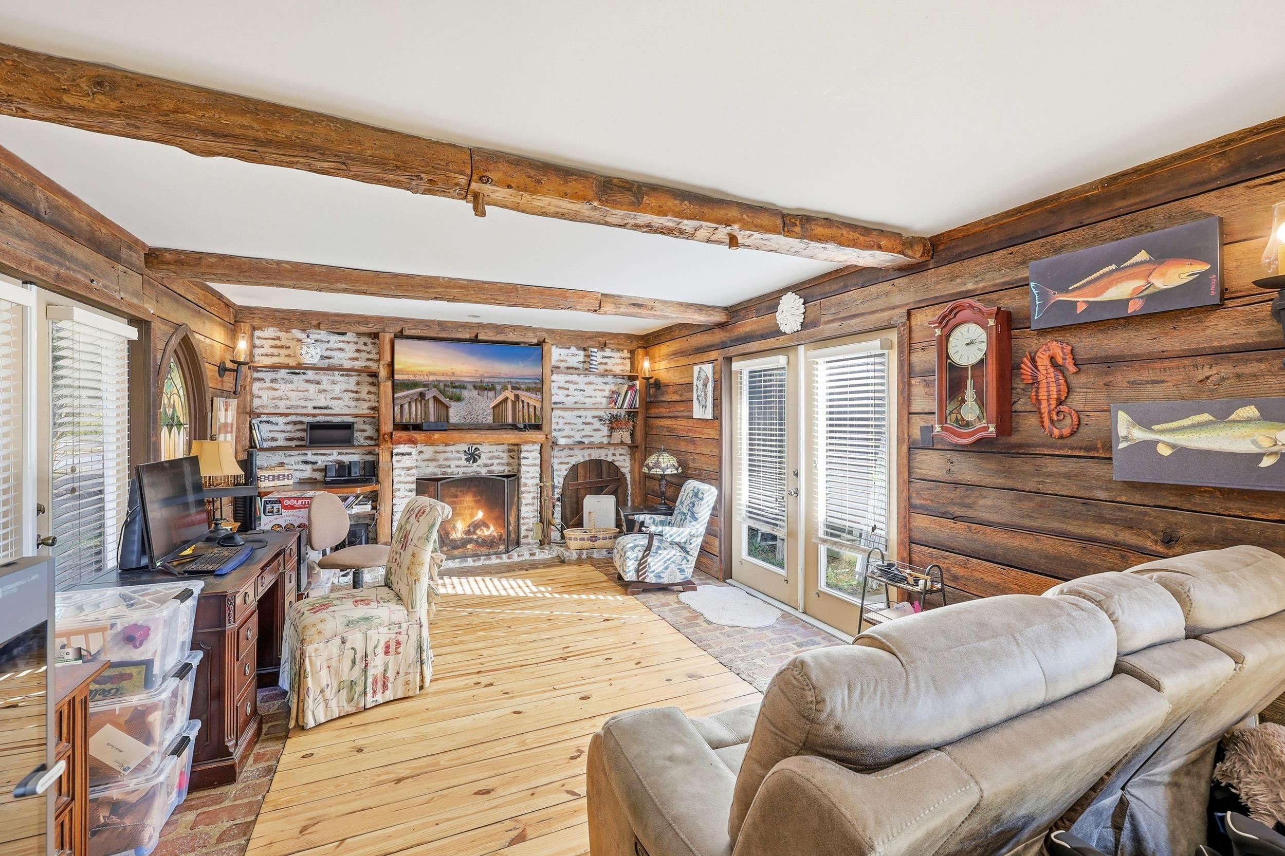 709 Mt Gilead Road Murrells Inlet, SC 29576 - Photo 11 of 38 Living area featuring wood-type flooring, a fireplace, beamed ceiling, and log walls