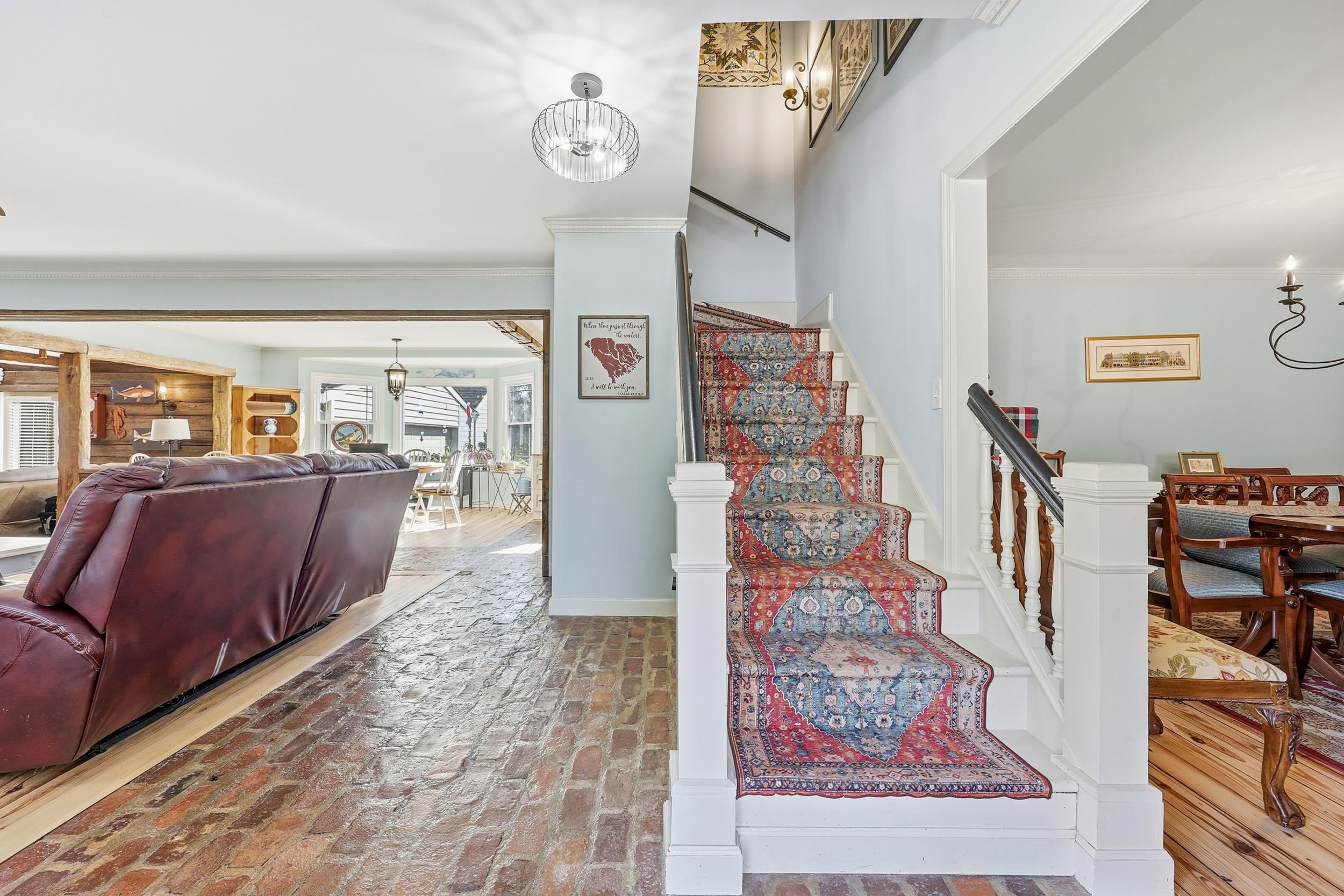 709 Mt Gilead Road Murrells Inlet, SC 29576 - Photo 2 of 38 Stairway featuring a chandelier, crown molding, and brick flooring