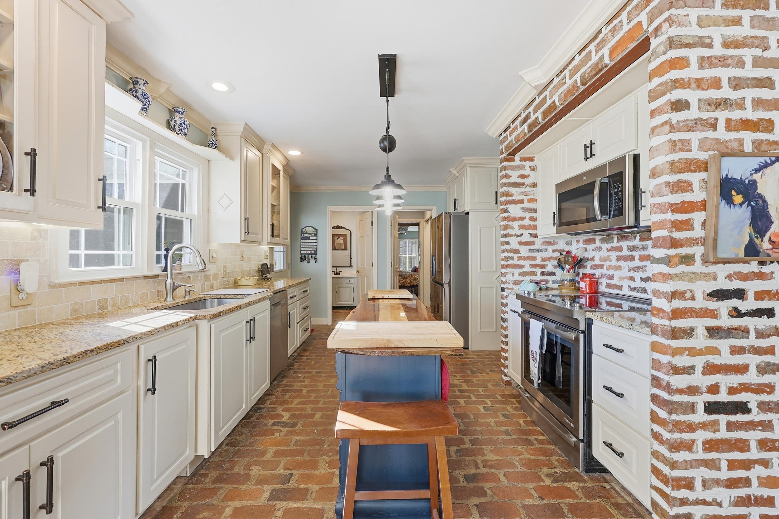 709 Mt Gilead Road Murrells Inlet, SC 29576 - Photo 9 of 38 Kitchen featuring appliances with stainless steel finishes, hanging light fixtures, ornamental molding, light stone counters, and brick floors