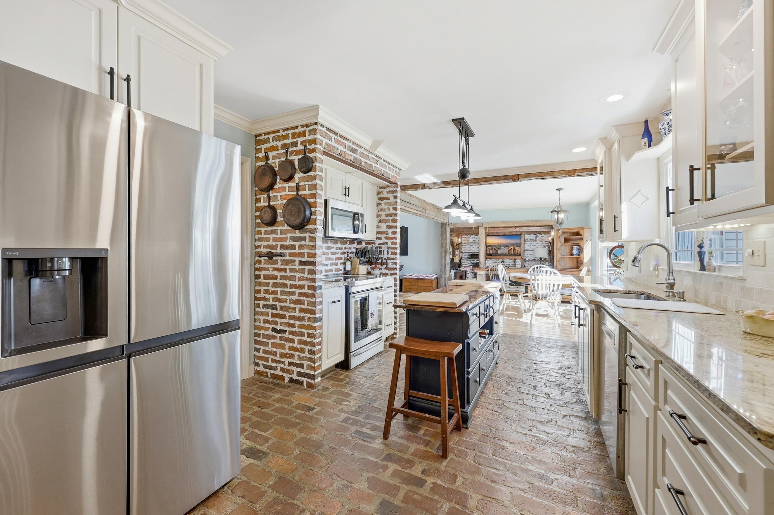 709 Mt Gilead Road Murrells Inlet, SC 29576 - Photo 10 of 38 Kitchen with appliances with stainless steel finishes, white cabinetry, brick floors, decorative light fixtures, and crown molding