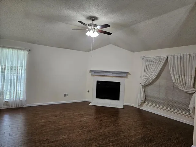 a view of an empty room with wooden floor fireplace and a window