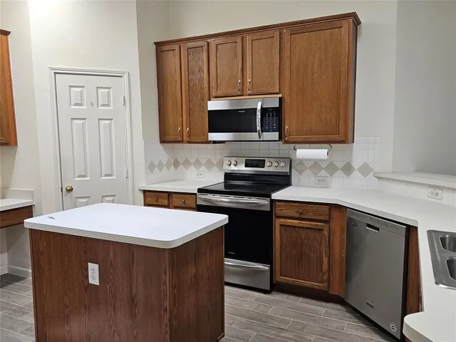 a kitchen with stainless steel appliances a sink a stove a microwave a sink and cabinets