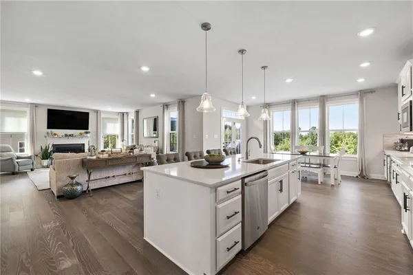a large kitchen with stainless steel appliances lots of counter space sink refrigerator and wooden floor
