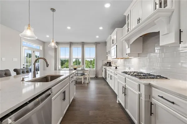 a kitchen with stainless steel appliances granite countertop sink stove and white cabinets with wooden floor