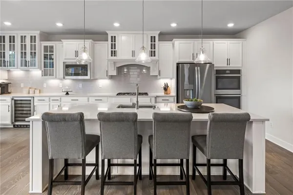 a kitchen with stainless steel appliances granite countertop a dining table chairs refrigerator and microwave