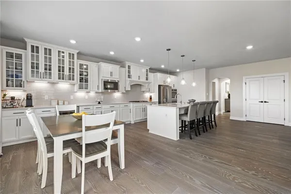 a kitchen with stainless steel appliances kitchen island granite countertop a table chairs and a refrigerator